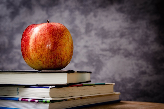 An apple sitting on a pile of books